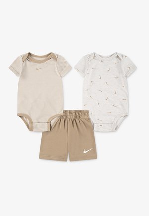 Deux bodies bébés à manches courtes beige—l’un rayé, l’autre avec de petits logos—et un short beige assorti à taille élastique, tous arborant le logo Nike swoosh blanc.