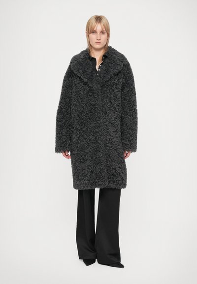 Dark gray faux fur coat with a large collar, long sleeves, and a relaxed fit, paired with black wide-leg trousers.
