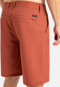 Herren-Shorts in Rostfarbe aus glattem Stoff mit zwei Gesäßtaschen, einem kleinen Markenschild und flachen maßgeschneiderten Nähten.