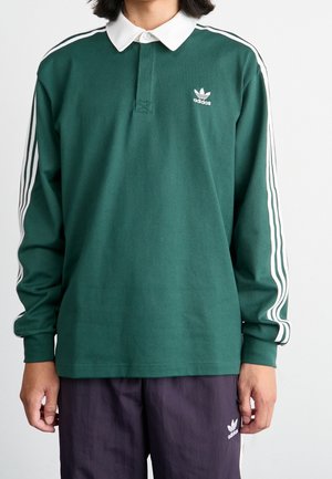 Grünes Langarm-Polohemd mit einem weißen Kragen, drei weißen Streifen an jedem Ärmel und einem kleinen weißen Adidas-Logo auf der Brust.