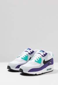 Baskets Nike Air Max en blanc et gris avec des accents violets et turquoise, dotées d'une tige en mesh, de lacets et d'une unité Air visible dans la semelle.