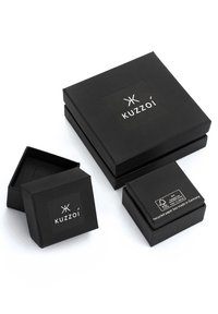 Schwarze Geschenkkartons aus Karton in verschiedenen Größen, mit dem Logo "Kuzzoí" auf einer matten Oberfläche und einem FSC-Label auf dem kleinsten Karton.