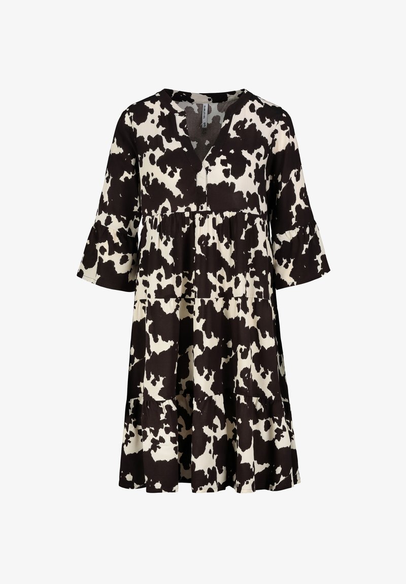 Schwarz-weißer Kuhflecken-Kleid mit V-Ausschnitt, flared Dreiviertelärmeln und gestuften Rüschensaum. Hergestellt aus weichem, leichtem Stoff.
