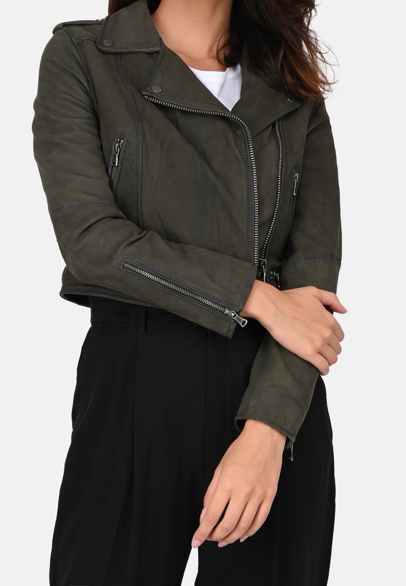 Veste de moto en cuir vert olive avec poches zippées et fermeture frontale asymétrique. Présente une silhouette ajustée et un col en revers.