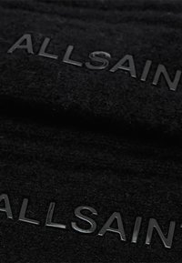 Schwarze Wollmütze mit erhabenem schwarzen Schriftzug "ALLSAINTS." Texturiertes Material mit einem weichen, gestrickten Aussehen.