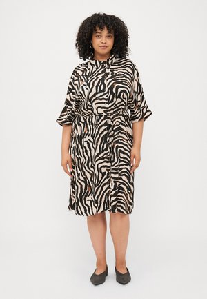 Short-sleeve dress featuring a beige fabric with black and brown zebra stripes, cinched at the waist with a drawstring, and button embellishments.