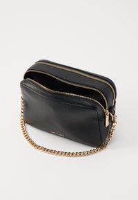 Black leather crossbody bag with two zippered compartments, gold chain strap, and textured finish. Features gold-tone hardware accents.