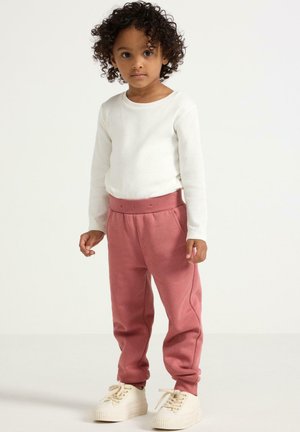 Witte lange mouwen ribbed shirt en roze joggingbroek met elastische tailleband. Witte sneakers met dikke zolen. Eenvoudig en comfortabel ontwerp.