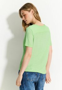Lysegrøn kortærmet t-shirt lavet af et struktureret stof, let løs pasform med rund hals og et enkelt design.
