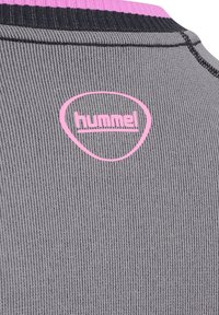 Szara sportowa koszulka o prążkowanej fakturze, z różowym logo Hummel na plecach i kontrastującymi czarnymi akcentami wokół kołnierza.