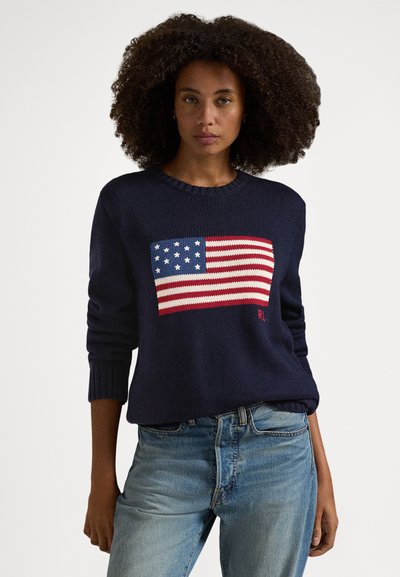Tmavě modrý pletený svetr s motivem americké vlajky v červené, bílé a modré barvě na přední straně. Žebrované manžety a límec. Ležérní střih.