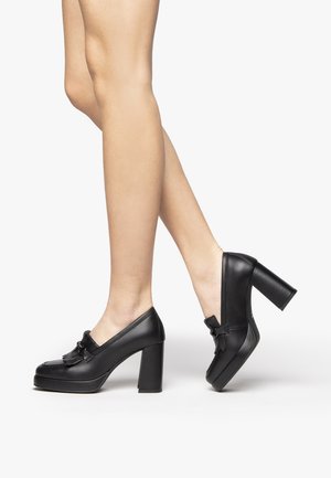 Scarpe nere in pelle con tacco alto, punta arrotondata, piattaforma e decorativo fiocco sul davanti. Il design con tacco a blocco offre stabilità.