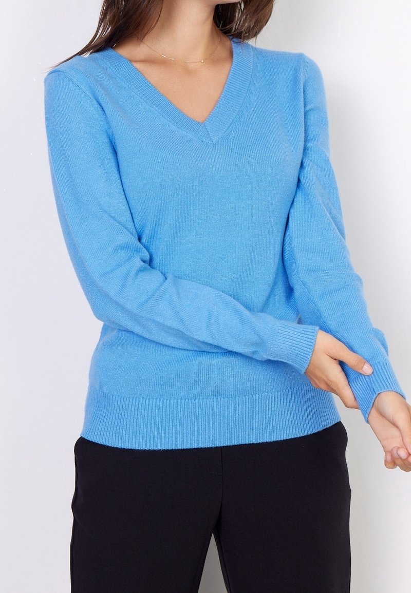 Helles blaues V-Ausschnitt-Pullover aus weichem Strickmaterial, mit gerippten Bündchen und Saum. Taillierte Passform mit langen Ärmeln, minimalistischem Design.
