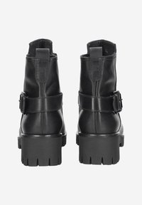 Black leather ankle boots with a rounded toe, strap detailing, and thick rubber soles featuring a tread pattern. Matte finish with a smooth texture.