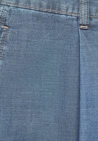 Primer plano de una tela de mezclilla azul que muestra el bolsillo frontal y el lazo del cinturón con detalles de costura en color marrón.