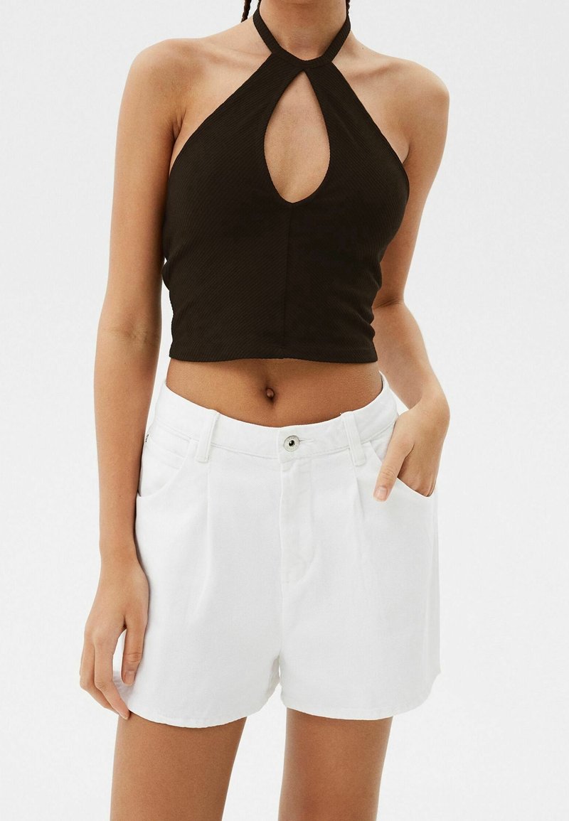 Svart ribbad halter-topp med nyckelhålsutskärning och hög halsringning, tillsammans med vita högmidjade shorts med sidofickor.