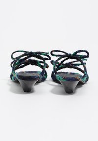Sandalias de tacón con tiras trenzadas en azul marino, verde y naranja, con un tacón bajo tipo cono y acabado texturizado. Las tiras se atan en la parte trasera.