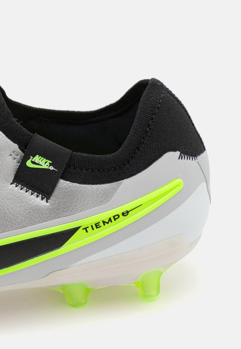 Botte de football Nike Tiempo avec une tige en synthétique grise, un talon noir, des accents vert vif, une texture douce et une semelle transparente avec des crampons.