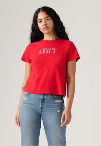 Rød avkortet t-skjorte laget av bomull, med rund hals og korte ermer. Fronten viser "LEVI'S" logo i hvit skrift.