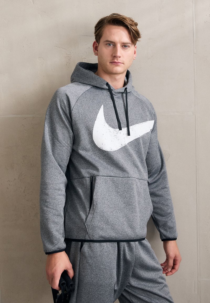 Felpa con cappuccio grigia e grande logo Nike bianco, con maniche raglan, tasca frontale zip e materiale in pile testurizzato.
