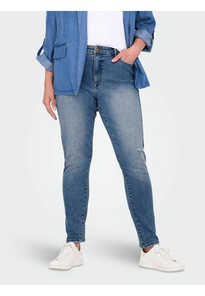 Skinny blue denim jeans with a faded finish, high waist, and five pockets, paired with a light blue button-up shirt and white sneakers.