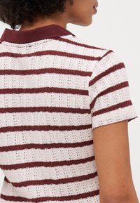 Stripet polo skjorte med en fargekombinasjon av maroon og krem, kort ermer, teksturert strikket stoff, og en ribbet krage.