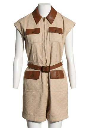 Combinaison beige sans manches avec col en cuir marron, ceinture et quatre poches à rabat avec boutons sur un mannequin blanc.