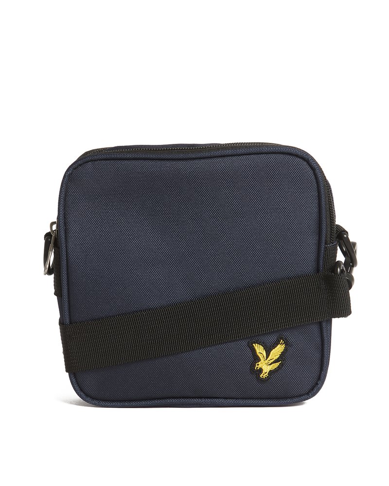 Borsa a tracolla quadrata blu navy con tracolla regolabile nera e piccolo emblema giallo a forma di uccellino nell'angolo inferiore destro della parte anteriore.