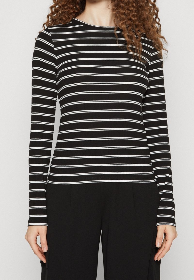 Långärmad svart och vit randig topp med rund halsringning, ribbad textur och figurnära passform. Matching med svarta byxor.