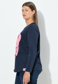 Camiseta de manga larga color navy con un gran diseño gráfico en rosa y una etiqueta de acento rosa en la parte inferior izquierda. Fabricada en suave algodón, con un corte relajado.