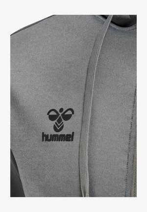 Nahaufnahme von grauem Hoodie-Stoff mit schwarzem hummel-Bienenlogo und Markennamen nahe der Brust, mit Kordelzug daneben hängend.