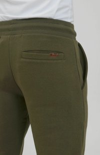 Maslinasto zelene trenirke od mješavine pamuka, s glatkom teksturom, elastičnim pojasom i jednim stražnjim džeparom s brend detaljem.