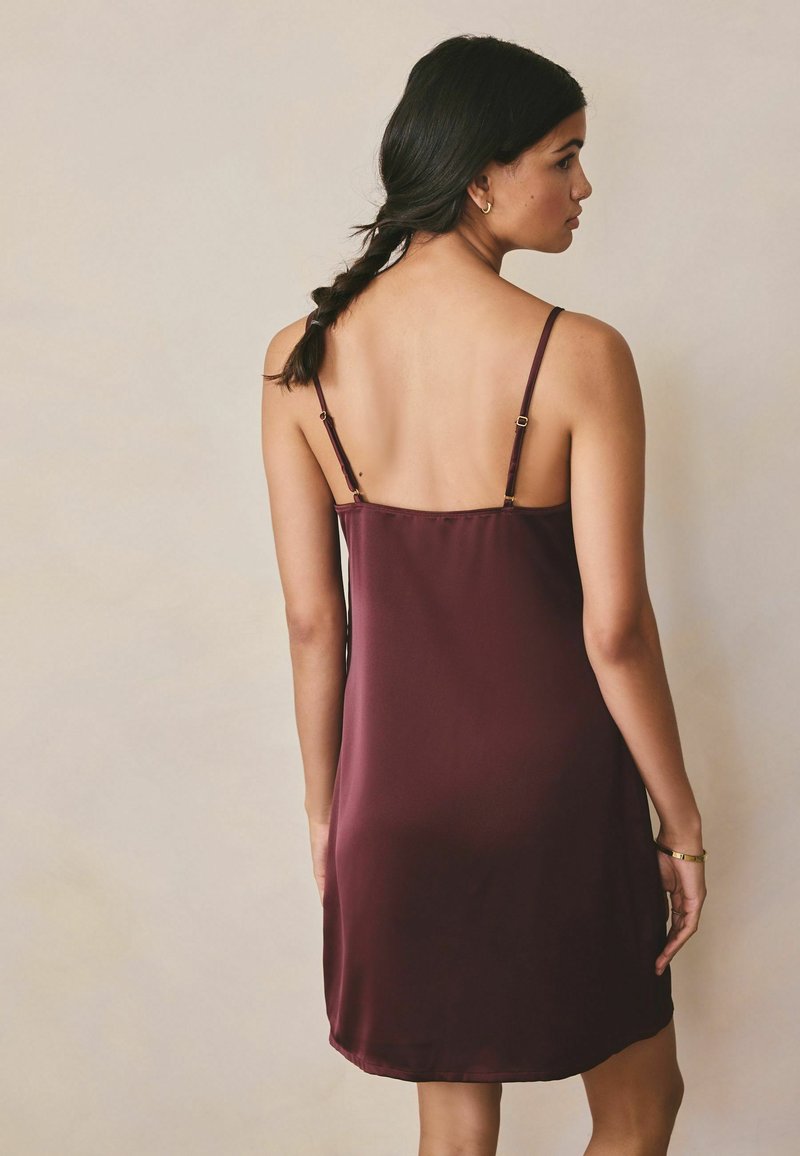 Rochie tip slip Marlburg în nuanță de burgund închis, din țesătură netedă, cu bretele subțiri ajustabile și croială dreaptă care ajunge deasupra genunchiului.