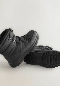 Bottes d'hiver noires avec un extérieur texturé, des lacets réglables et des semelles en caoutchouc dotées de motifs de traction. Doublure douce pour la chaleur.