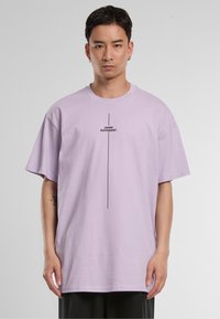 Short-sleeve lavender t-shirt in cotton, featuring black text "THINK DIFFERENT." centered vertically. Relaxed fit with dropped shoulders.