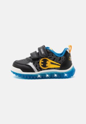 Čierno-modrá detská teniska so žltým Batman logom, dvoma suchými zipsami a svietiacou modrou podrážkou na bielom pozadí.