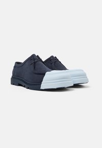 Scarpe in suede blu navy con una profilo basso, punta arrotondata e punte in gomma azzurro chiaro. Presentano lacci e pannelli laterali testurizzati.