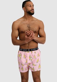 Pink boxer shorts feature a playful banana pattern and a black elastic waistband with "LOUSY LIVIN" text. Lightweight fabric and loose fit.