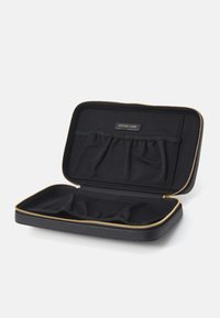Étui noir zippé fabriqué en matériau texturé, avec une fermeture éclair dorée, plusieurs poches intérieures et une étiquette de marque. L'intérieur est également noir.