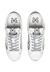 Scarpe da ginnastica bianche con lacci glitterati argento, materiale in pelle e dettagli in logo nero. Presentano un design elegante e una forma della punta arrotondata.