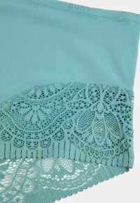 Intimo di colore aqua con una texture di tessuto liscia, caratterizzato da raffinati dettagli in pizzo lungo l'orlo inferiore e bordi scallop.