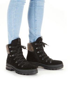 Black suede ankle boots with a textured brown cuff, lace-up front, metal eyelets, and sturdy rubber soles.