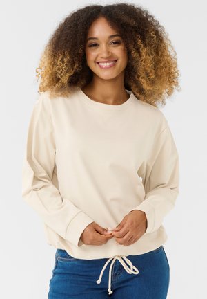 Helles beiges Sweatshirt mit langen Ärmeln, rundem Ausschnitt und verstellbarem Kordelzug am Saum. Weicher Stoff mit glatter Textur.