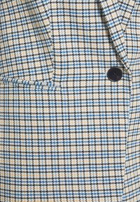 Blazer a quadri con motivi blu, gialli e neri. Presenta un colletto con punta e un singolo bottone nero, realizzato in tessuto testurizzato.