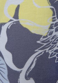 Bloemmotiefstof met grijze, gele en witte kleuren, met een gestructureerde weving en abstracte designelementen.