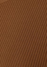 Hnědá ribová látka s texturovaným povrchem, která má vertikální pruhy a jemný pletený vzhled.
