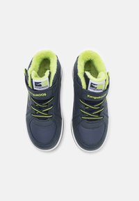 Marineblauwe high-top sneakers met zwarte accenten, groene voering en limoen groene veters. Witte rubberen zool en logo op de tong. Zachte textuur.