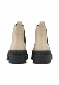 Béžové syntetické kožené kotníkové boty s černými elastickými bočními panely a silnými černými gumovými podrážkami. Vlastností je poutko na zadní straně pro snadné obouvání.