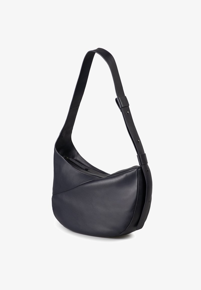 Borsa a spalla in pelle nera con una forma curva e asimmetrica, una tasca con zip e una tracolla regolabile. Texture liscia con hardware minimale.
