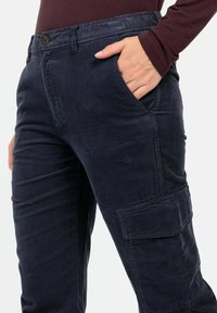 Marineblauwe corduroy cargobroek met een zijzak, knoopsluiting en een licht gestructureerde afwerking. Slank model en duurzaam materiaal.